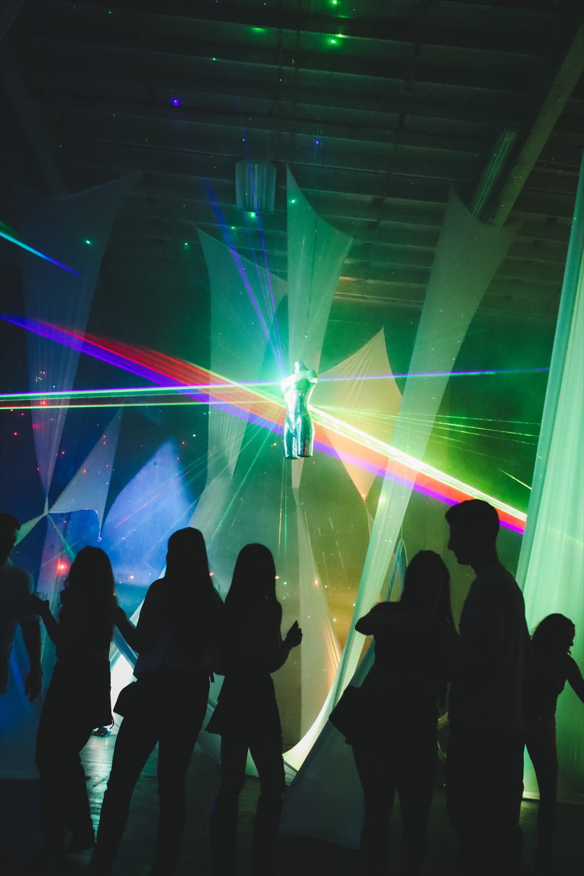 Guests weaving through suspended fabric beneath Disco B*tch and colorful laser beams
