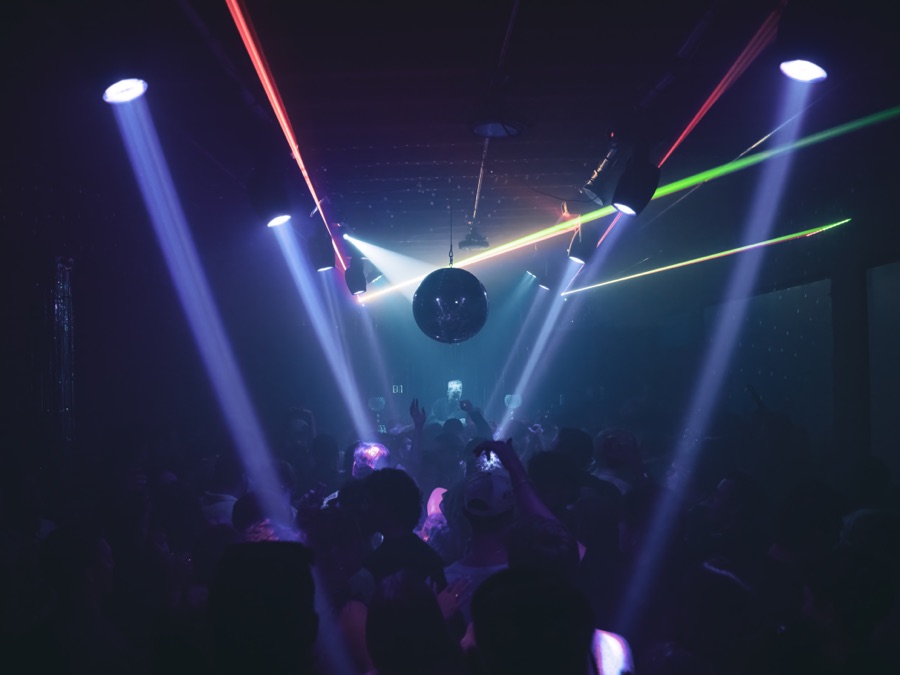Crowded dance floor beneath a disco ball and lasers