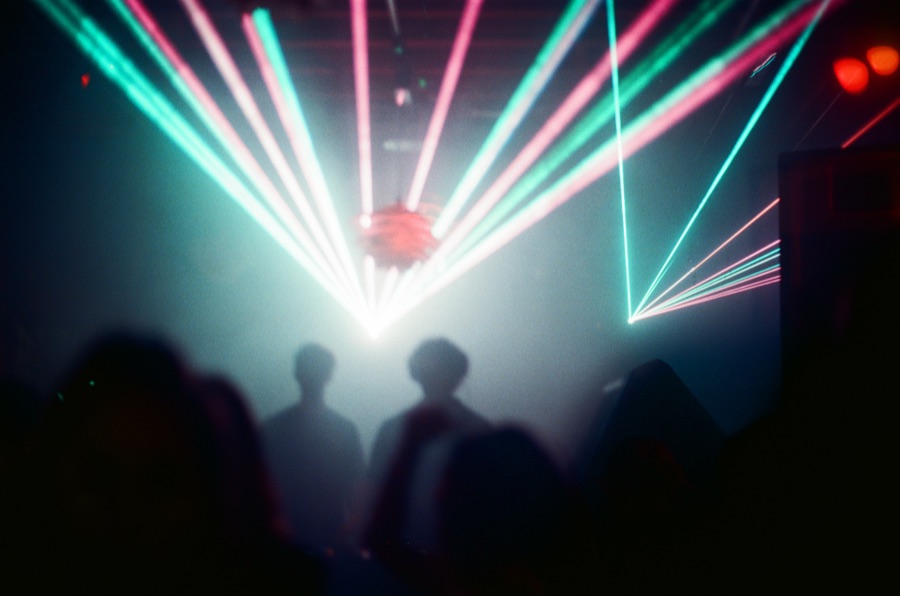 Colored laser beams cutting across a dark dance floor